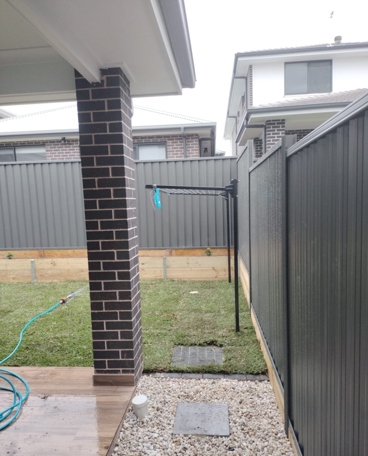 Back yard seen from the alfresco: turf, a timber sleeper wall with plantings and a pebble strip along the fence
