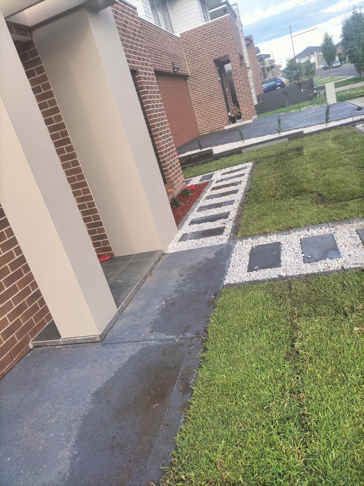 Front garden bed edged with pavers and white pebble beside fresh turf and a driveway